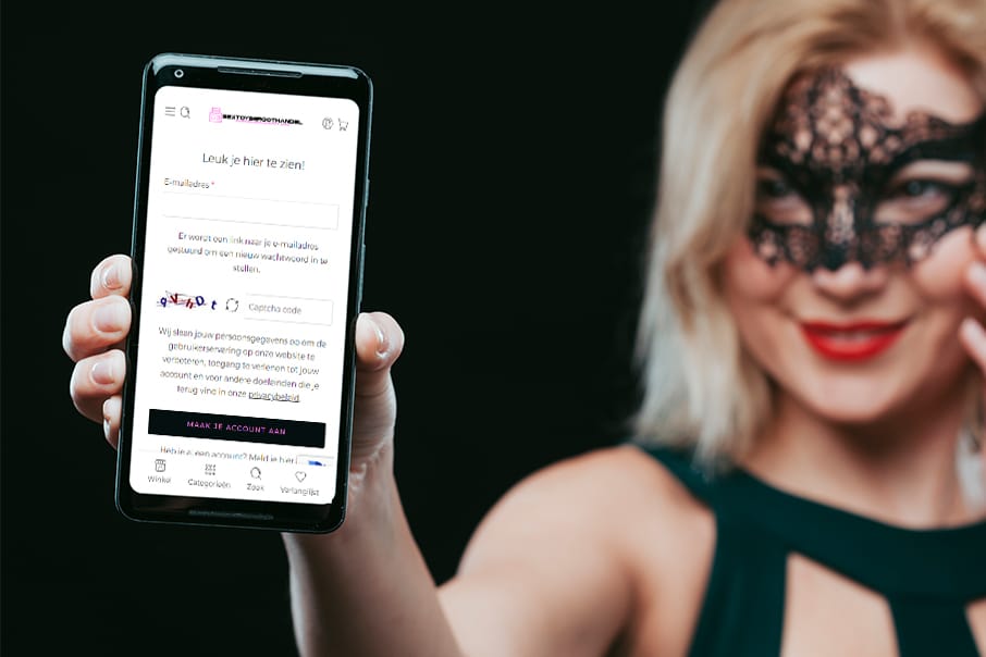 Vrouw met zwarte kantmasker houdt een smartphone vast waarop de registratiepagina van Sextoysgroothandel.nl wordt weergegeven